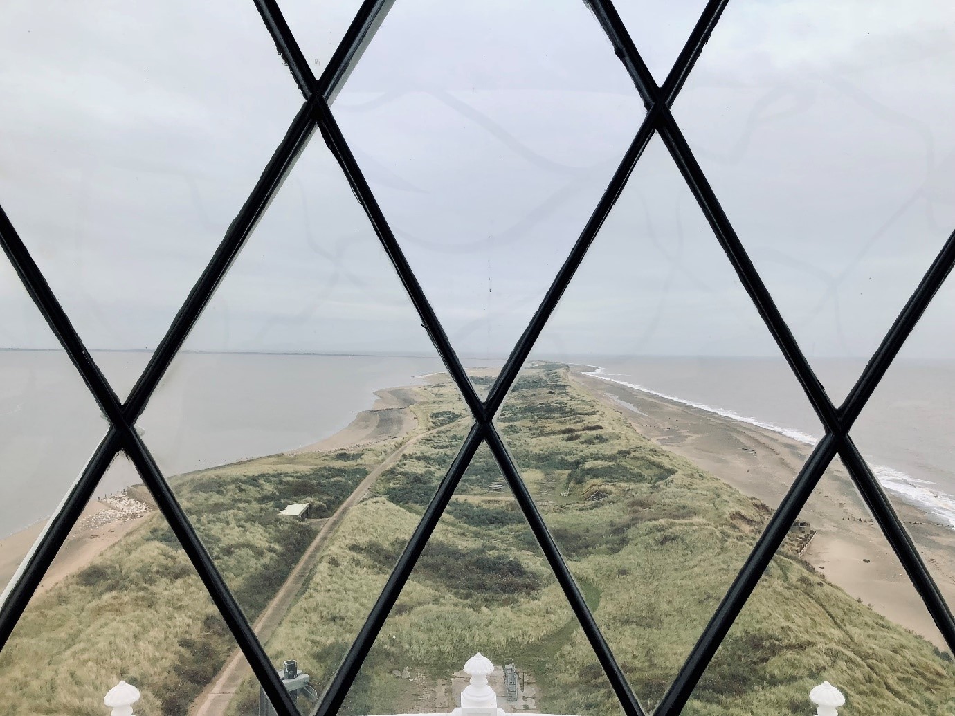 A view from the top of Spurn Point lighthouse looking out to the end of the narrow spit of land with the sea and the Humber Estuary either side
