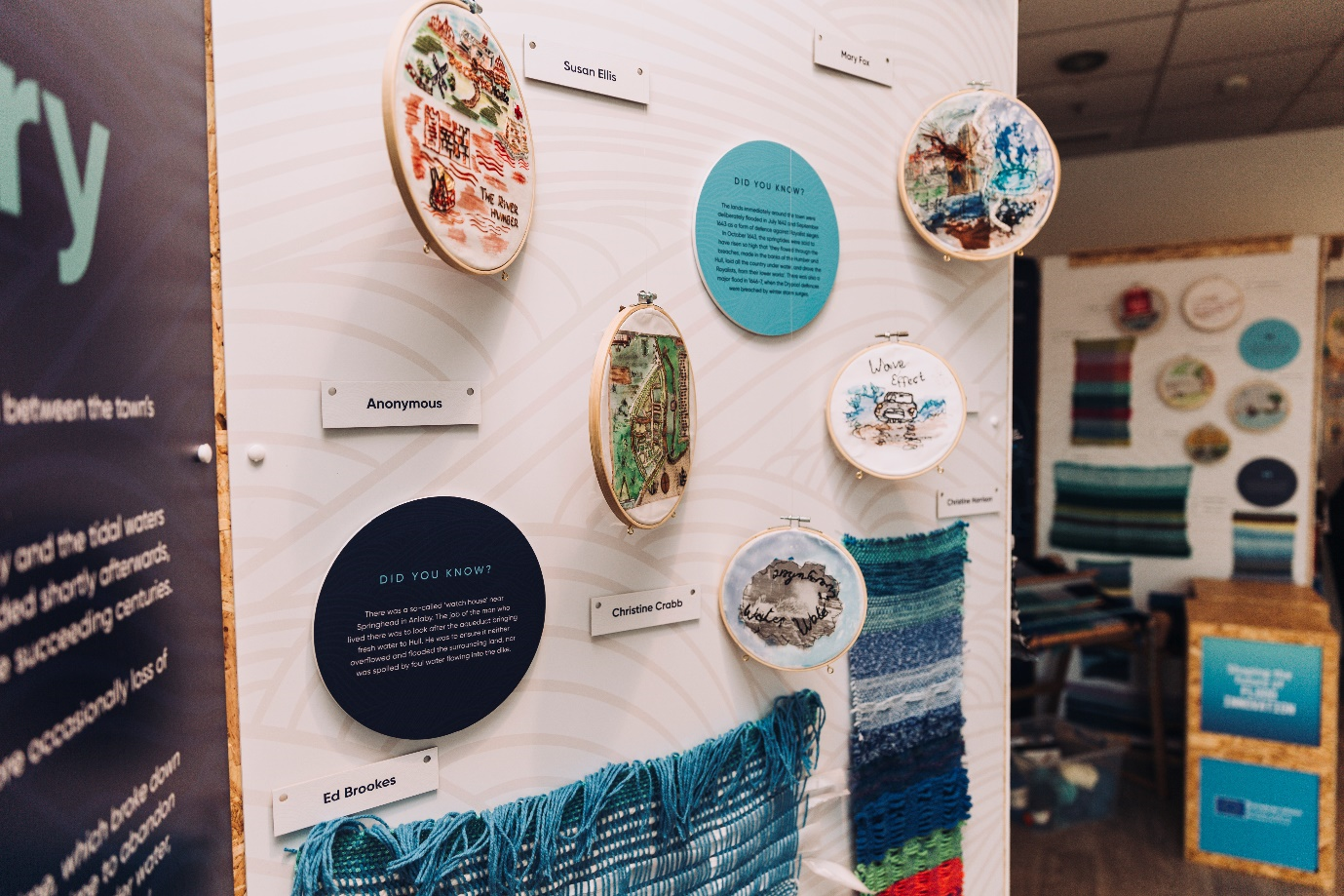 A display of woven and embroidered textile art fhanging from a display board as part of the ‘Follow the Thread’ exhibition