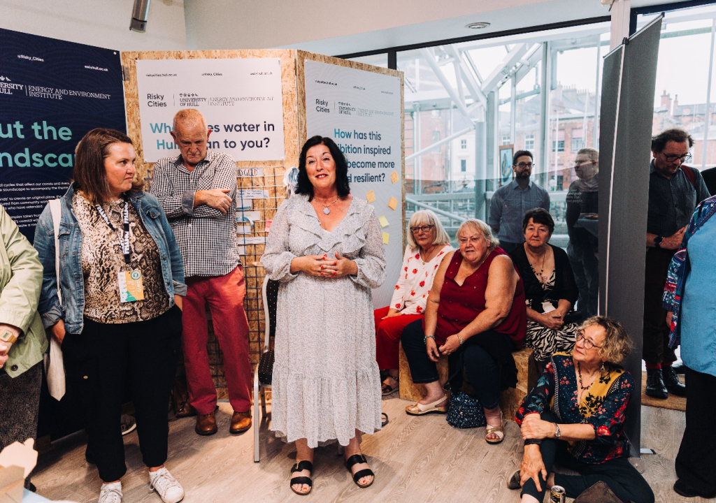 Dawn Sullivan and members of the Cottingham and HU4 community groups stand and sit in the exhibition space for Follow the Thread textiles exhibition